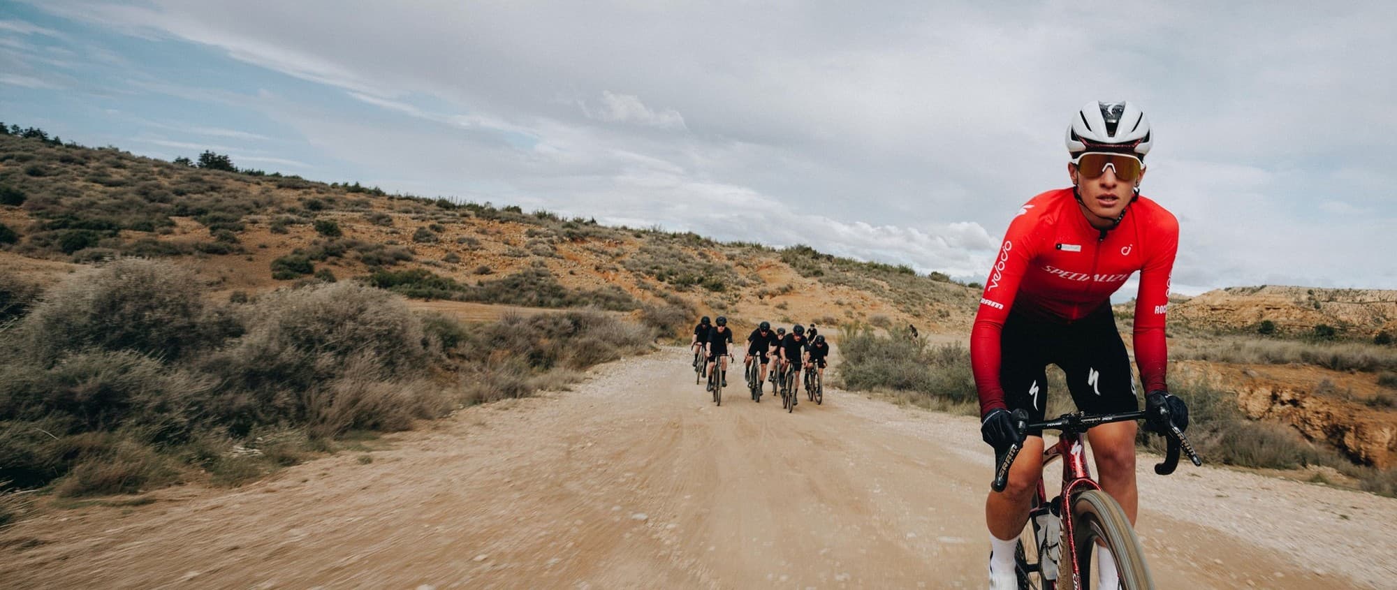 Crux 5 riders racing a desert gravel road, lead rider in red